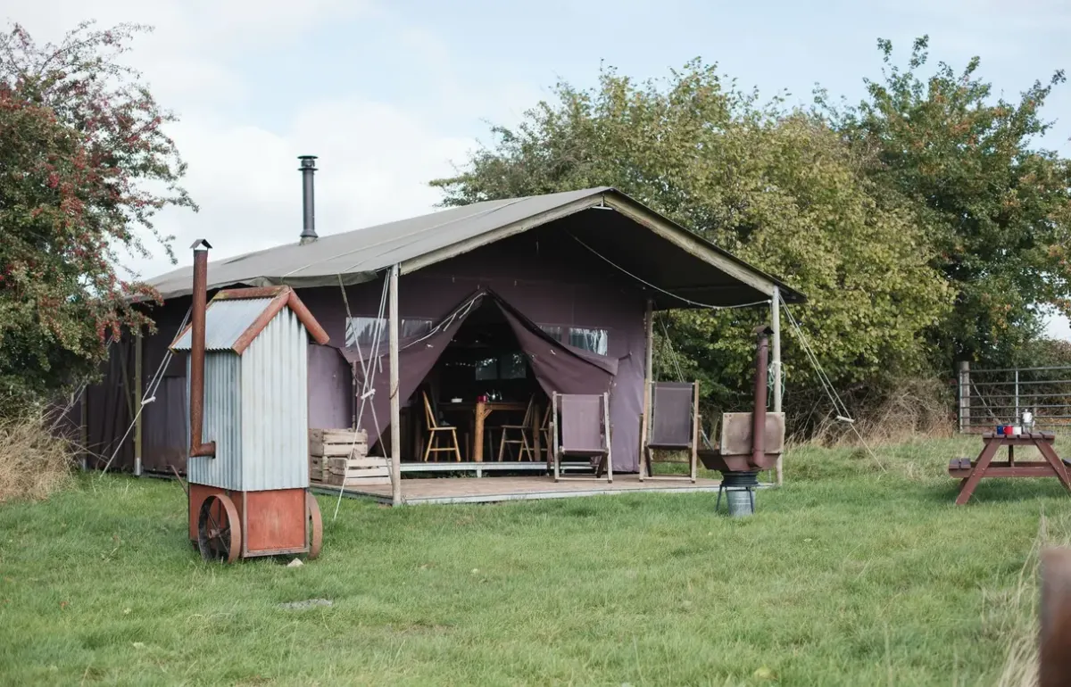Safari tents at Hollings Hill Farm in the Cotswolds have a covered veranda with a picnic table outside
