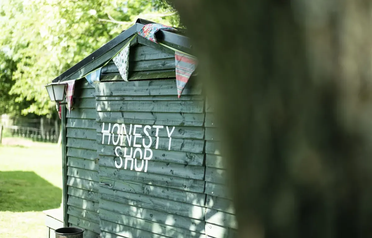 The painted wooden honesty shop with bunting at Feather Down Sunninglye